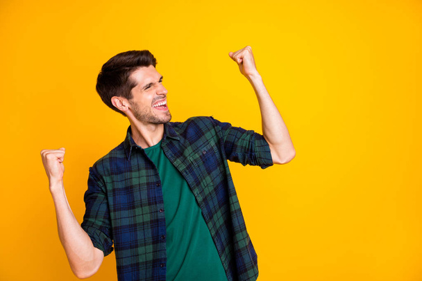 Photo of cool guy worried about football game raising fists supporting team wear casual plaid shirt isolated yellow color background - 写真・画像