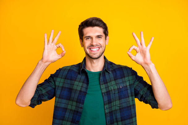 Photo of amazing macho guy showing okey symbols expressing positive mood wear casual plaid shirt isolated yellow color background - Фото, изображение