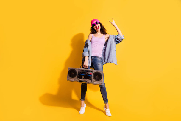 Full body photo of crazy lady with big tape recorder listening metal song making horns symbol wear casual trendy clothes isolated yellow color background - Фото, зображення