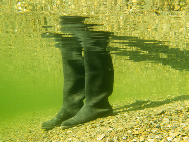 rubberen laarzen of gumboots onderwater op zand grond - Foto, afbeelding