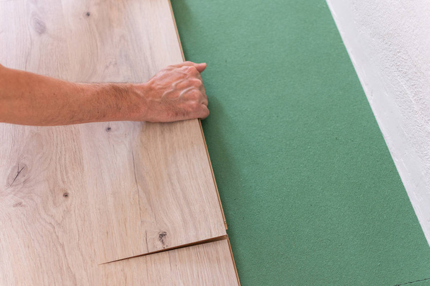 Worker installing wooden laminate flooring - Photo, Image