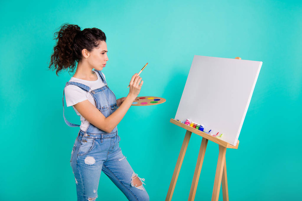 Portrait of nice attractive focused concentrated minded wavy-haired girl wearing casual holding in hands water color making new picture isolated on bright vivid shine green turquoise background - Φωτογραφία, εικόνα