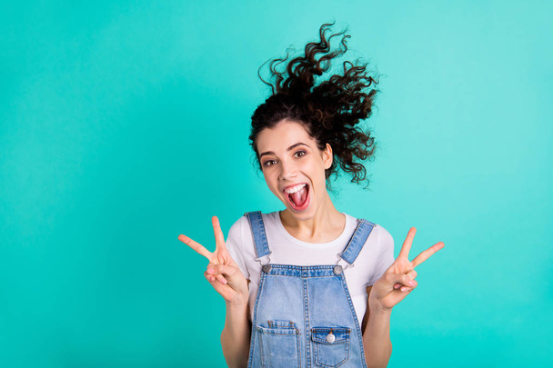 Close-up portrait of her she nice attractive charming cheerful cheery positive wavy-haired girl wearing blue overall showing v-sign isolated on bright vivid shine green turquoise background - Φωτογραφία, εικόνα