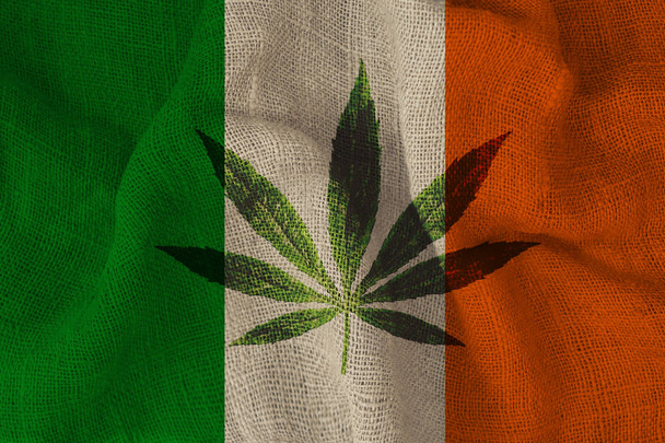 green leaf of hemp and the beautiful national flag of Ireland, the concept of medical cannabis, legalization of drugs, drug trafficking crimes, close-up - Photo, image