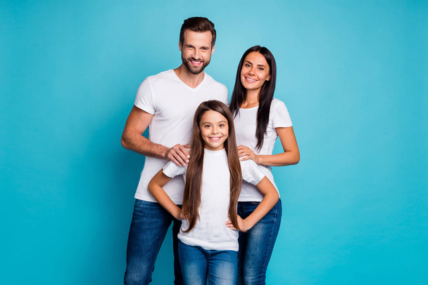 Portrait of charming family smiling wearing white t-shirt isolated over blue background - Fotó, kép