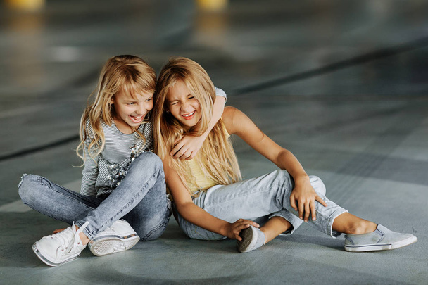 Dos hermosas chicas de skate, divirtiéndose y jugando en el estacionamiento. Sesión de fotos callejeras
 - Foto, Imagen