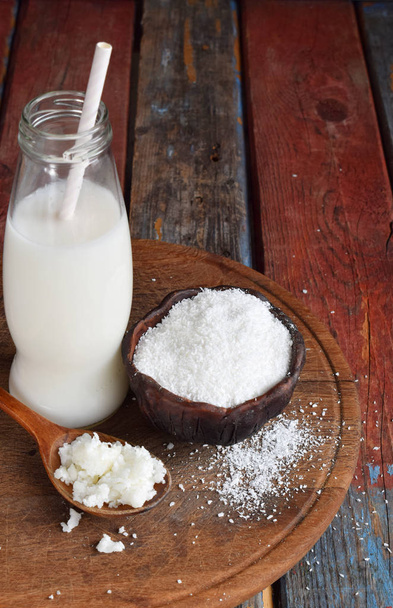 Coconut milk and oil with broken coco on wooden background. Delicious milk cocktail. Copy space. - Photo, Image