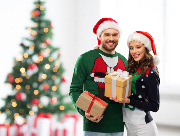 happy couple in sweaters with christmas gifts - Zdjęcie, obraz