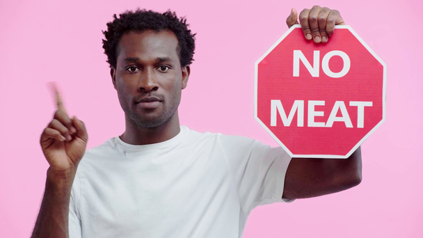 serious african american man holding no meat card isolated on pink - Footage, Video