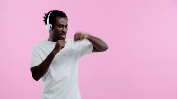 happy african american man dancing in headphones isolated on pink - Footage, Video
