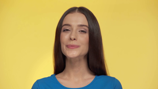attractive girl winking eye isolated on yellow - Felvétel, videó
