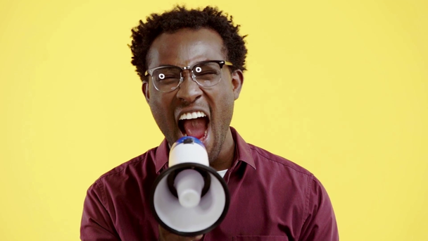 wściekły Afrykanin amerykański człowiek kłócący się na głośnik odizolowany na żółto - Materiał filmowy, wideo