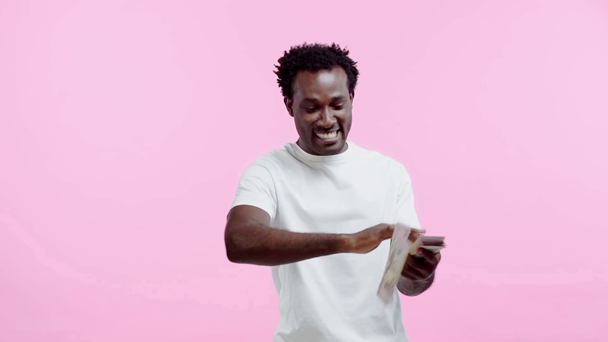 câmera lenta do homem americano africano segurando dólares isolados em rosa
 - Filmagem, Vídeo