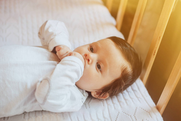 Cute little baby in white clothes close portrait, lying in bed at home - Фото, изображение