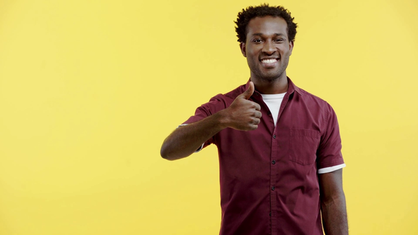 cheerful african american man showing thumb up isolated on yellow - Video, Çekim