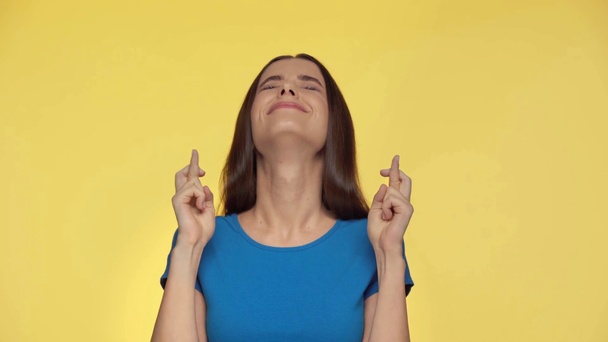 ανήσυχος κορίτσι με σταυρωμένα δάχτυλα απομονώνονται σε κίτρινο - Πλάνα, βίντεο