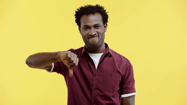 незадоволений афроамериканський чоловік показує великий палець вниз ізольовано на жовтому
 - Кадри, відео