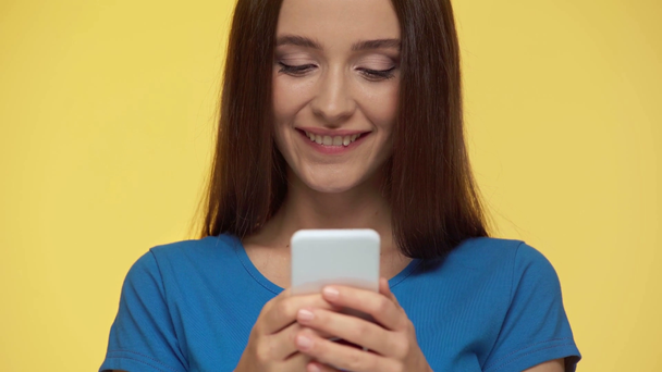 selective focus of girl texting on smartphone isolated on yellow - Footage, Video
