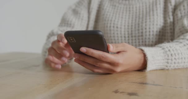 Front view mid section of a young woman sitting at a table using a smartphone - Filmagem, Vídeo