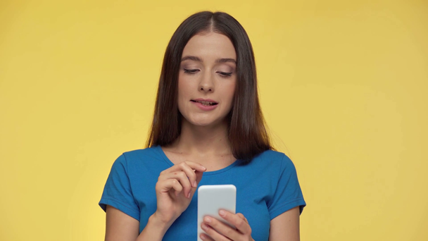 pensive and worried girl using smartphone isolated on yellow - Footage, Video