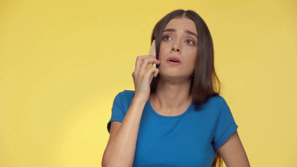 φοβισμένη γυναίκα που μιλάει στο smartphone απομονωμένη στο κίτρινο - Πλάνα, βίντεο