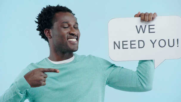 cheerful african american employer holding we need you speech bubble isolated on blue - Footage, Video