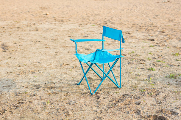 Concept de fin de saison, vacances et solitude - Chaise bleue sur la plage
 - Photo, image