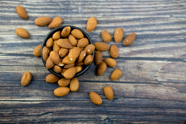 Almond in bowl on wooden background. Tasty healthy snack.  - Photo, Image