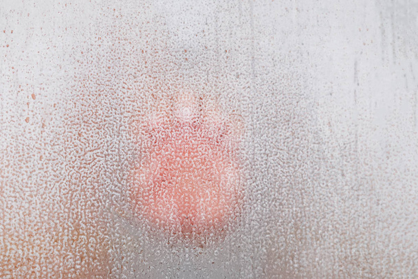 Mans mão close-up através do vidro do chuveiro de vidro enevoado com gotas
 - Foto, Imagem