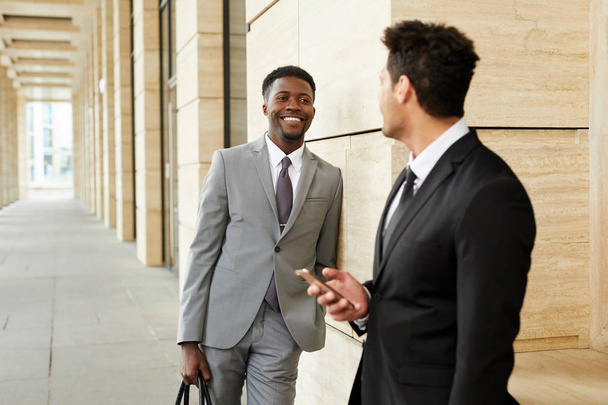 Successful multiethnic businessmen in formal clothing standing outdoors near the modern building  - Foto, Bild