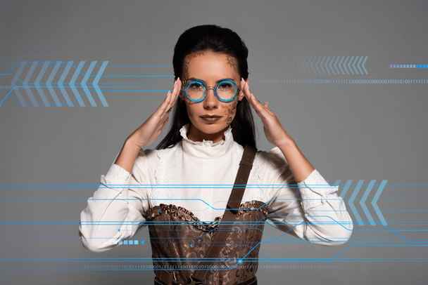 Steampunk-Frau berührt Brille isoliert auf Grau mit Daten-Illustration - Foto, Bild