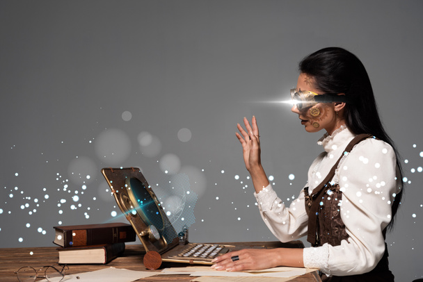 steampunk woman in goggles waving hand during video chat with glowing digital illustration isolated on grey - Фото, зображення