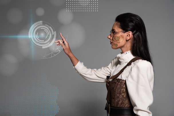 cropped view of steampunk young woman in white blouse pointing with finger at digital illustration on grey - Foto, afbeelding