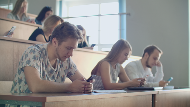 Multi etniczne grupy uczniów za pomocą smartfonów w czasie wykładu. Młodych ludzi za pomocą mediów społecznych podczas nauki na Uniwersytecie. - Materiał filmowy, wideo