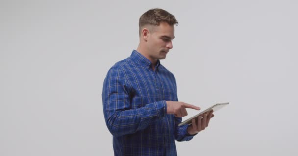 Side view close up of a young Caucasian man standing using a tablet computer and smiling - Footage, Video