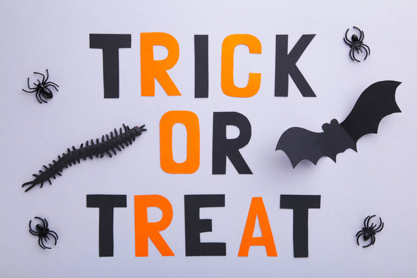 Inscription halloween with paper bats with spiders on grey background. Halloween concept - 写真・画像