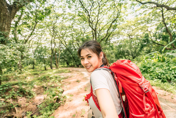 Щаслива жінка з Азії, з рюкзаком, що ходить лісом. - Фото, зображення