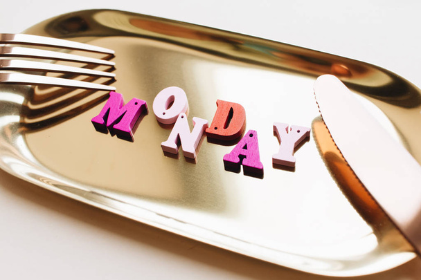 colorful wooden letters on metal tray with fork and knife, MONDAY lettering  - Foto, imagen