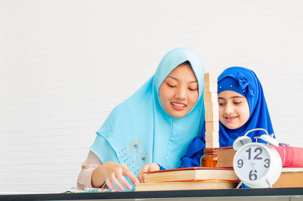 Madre musulmana e sua figlia con hijab blu giocano insieme nella stanza con tenda bianca
. - Foto, immagini