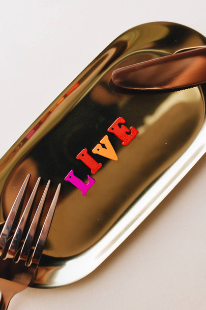 colorful wooden letters on metal tray with fork and knife, LIVE lettering  - Photo, Image