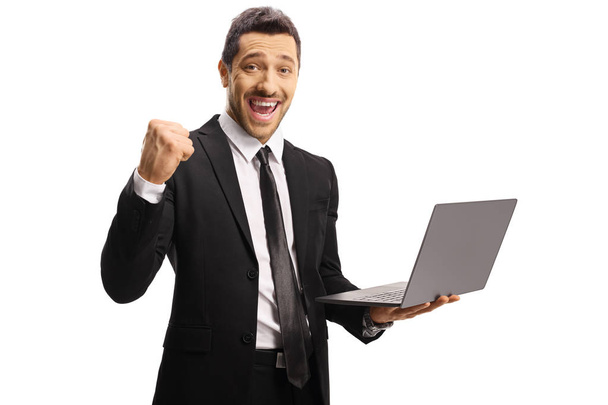 Young businessman gesturing yeah and holding a laptop computer - Photo, image
