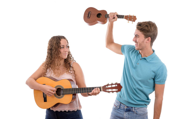dos jóvenes hermanos caucásicos o pareja tocando una guitarra y un ukelele divirtiéndose juntos en una fiesta con fondo blanco aislado
 - Foto, imagen