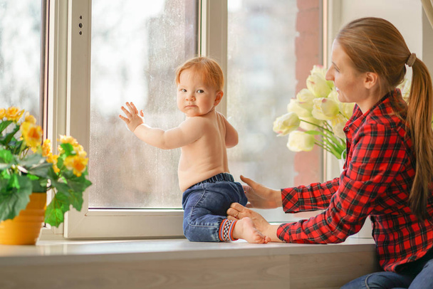 Mãe e filho pequeno sentados em um peitoril da janela e esperando
. - Foto, Imagem
