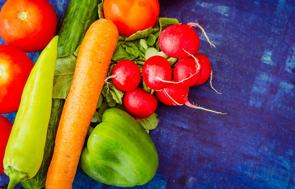 Rajčata s paprikou, ředkvička, okurky a mrkev na modrém pozadí - Fotografie, Obrázek
