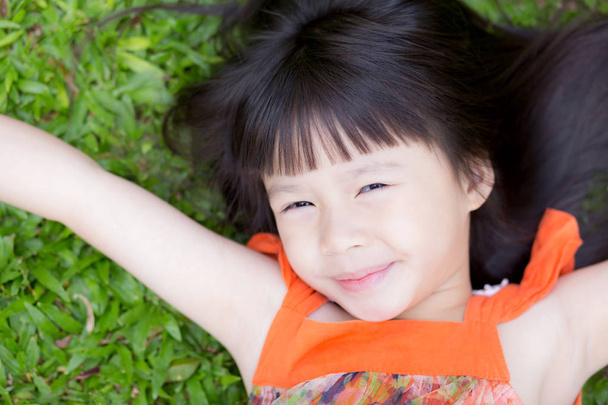 Krásná portrétní holčička, Asijská, usmívající se ležící na zeleném - Fotografie, Obrázek