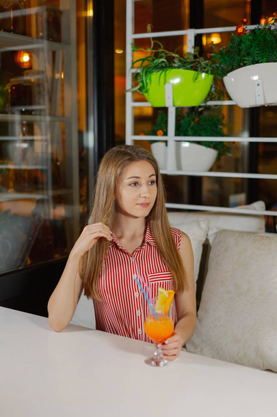 Красивая девушка с ярким свежим коктейлем в кафе
. - Фото, изображение