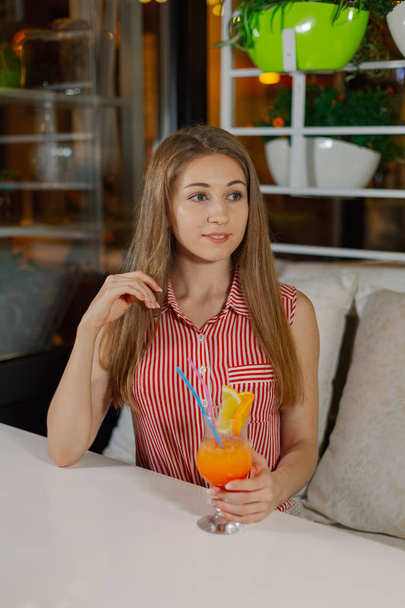 Beautiful girl with a bright fresh cocktail in a cafe. - Fotoğraf, Görsel