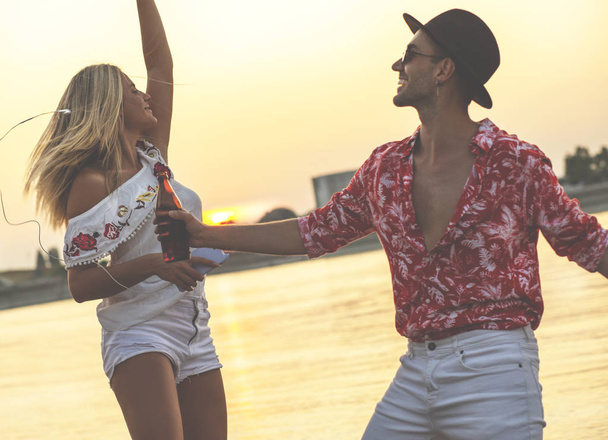Друзі танцюють разом на пляжі. Щасливі молоді люди розважаються на пляжі
. - Фото, зображення