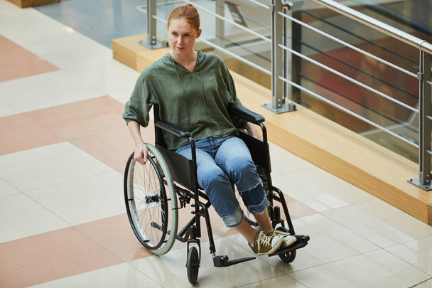 Jovem ruiva sentada em cadeira de rodas no hospital moderno
 - Foto, Imagem