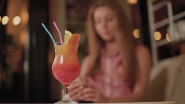 Mooi meisje met een mooie frisse heldere lichte avond cocktail in een café. - Video
